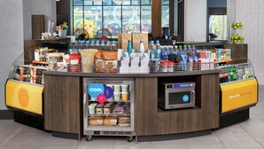 A self-service beverage station with refrigerated drinks, snacks, and a coffee machine. - Home2 Suites by Hilton Nashville Downtown Convention Center (Nashville)