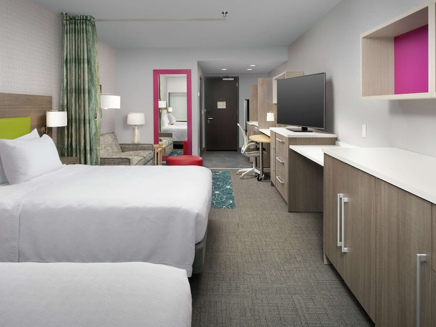 Een hotelkamer met twee bedden, een bureau, een televisie en een badkamer.