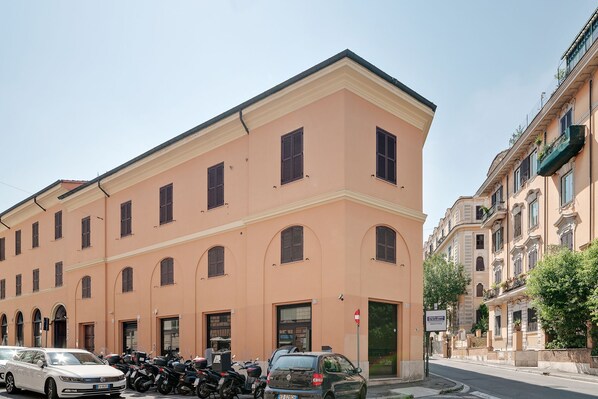 A two-story building with a peach facade, multiple windows, and a door. - Peroni Apartment (Rome)