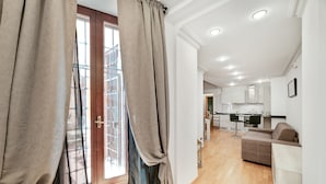 A modern apartment with a wooden floor, a dining area, a kitchen, and a living room with a sofa. - Peroni Apartment (Rome)
