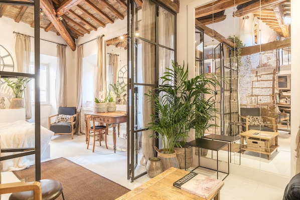 Relax in a spacious room with a high ceiling, comfortable seating area, and large window.