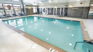 An indoor swimming pool with lounge chairs, a diving board, and a 'No Diving' sign.