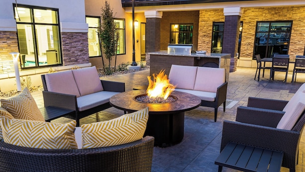 An outdoor patio area with wicker furniture, a fire pit, and a stone wall.