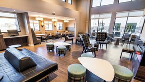A spacious lounge area with leather sofas, plaid ottomans, and a variety of seating options.