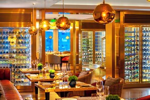A well-lit restaurant with tables set for dining, wine racks, and a view of the city. - Hotel Indigo Shanghai Jing'An by IHG (Shanghai)