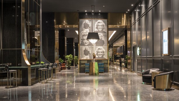 A modern lobby with a reception desk, seating area, and a large wall with photos. - Hotel Indigo Shanghai Jing'An by IHG (Shanghai)