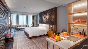 A modern hotel room with a bed, a desk with a fruit tray, a minibar, and a large abstract painting on the wall. - Hotel Indigo Shanghai Jing'An by IHG (Shanghai)