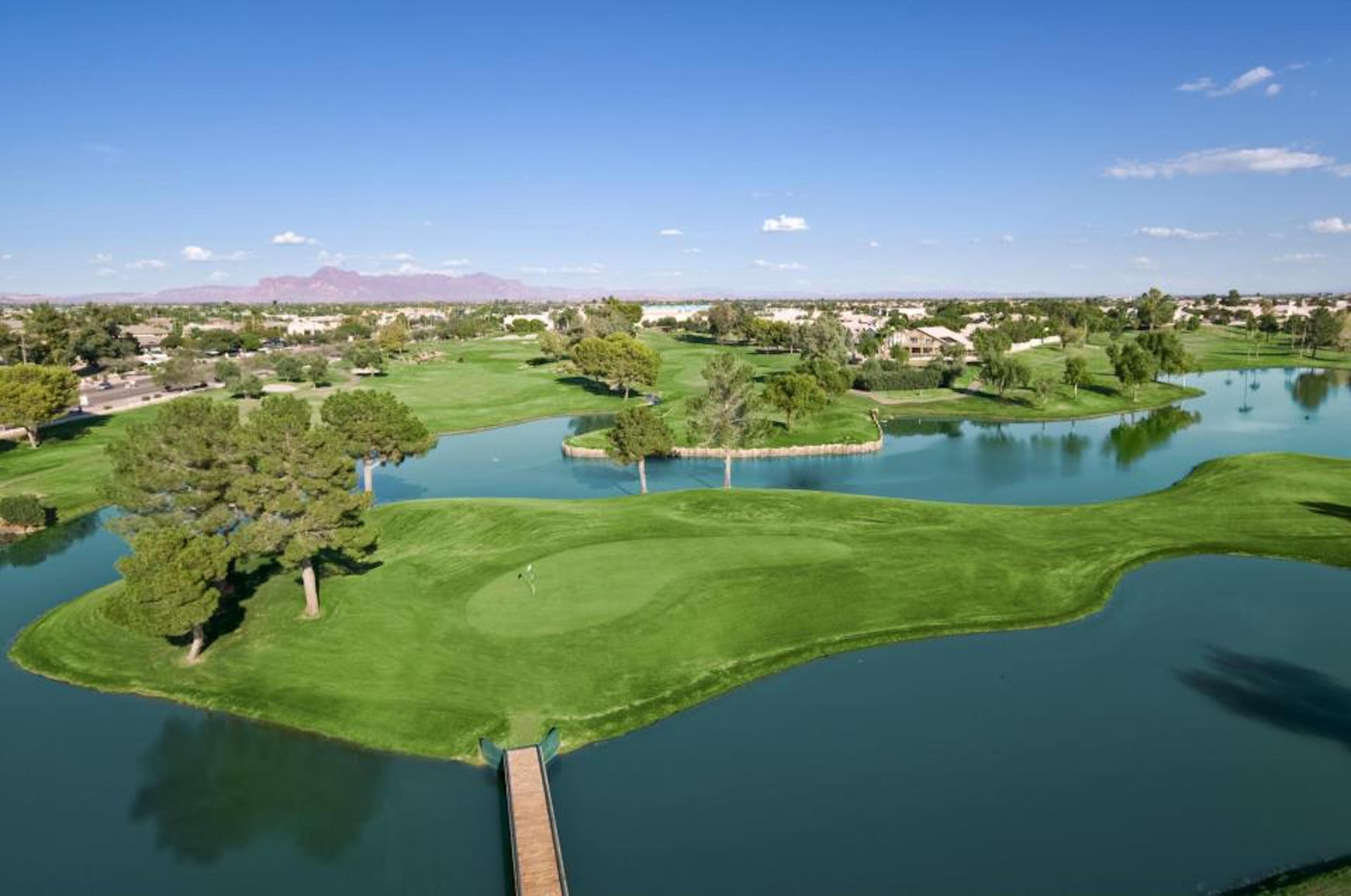 A golf course with water hazards, a wooden dock, and a clear view of the surrounding landscape.