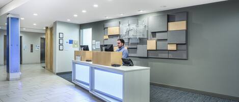 A modern reception area with a reception desk, a blue pillar, and a wall-mounted information board.