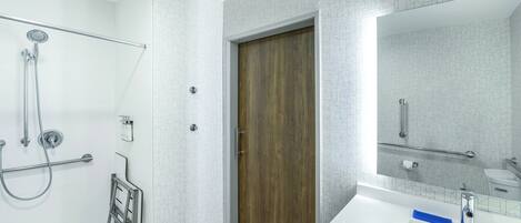Une salle de bain moderne avec une douche, une porte en bois, un lavabo blanc et un miroir.