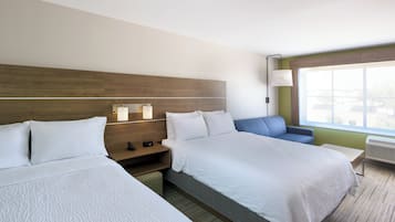 Ein Hotelzimmer mit zwei Betten, einem Nachttisch, einem Schreibtisch, einem Stuhl und einem großen Fenster.
