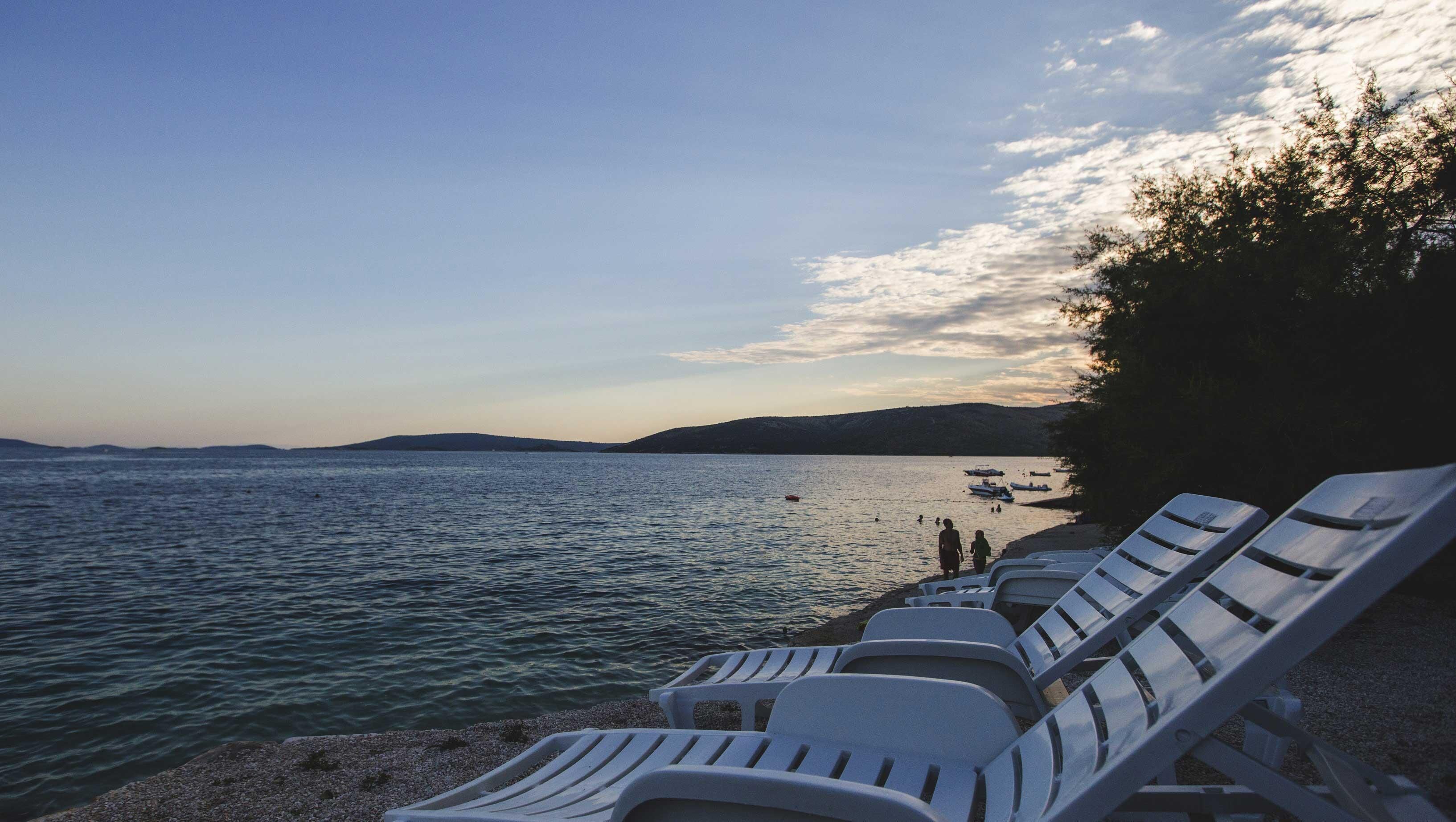 A beach with lounge chairs and a calm sea.