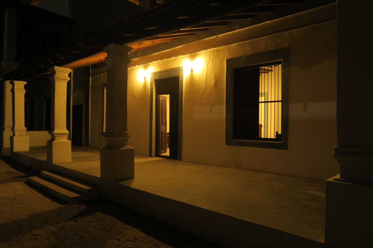 Un edificio con vestíbulo cubierto, columnas y una ventana con cortinas.