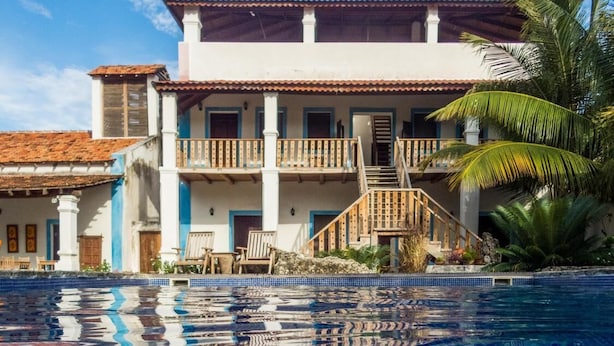 A hotel with a swimming pool, a balcony, and a staircase leading to the upper floor.