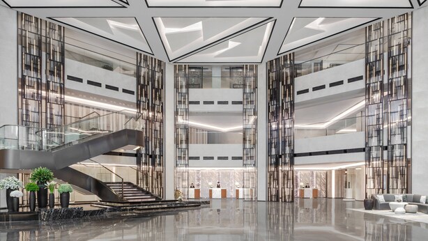 Un hall d’entrée spacieux avec un escalier central, de hauts plafonds et un éclairage moderne.