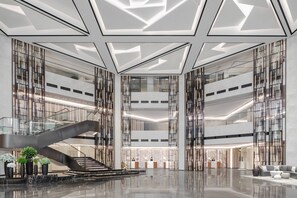 A spacious lobby with a central staircase, high ceilings, and modern lighting. - Xiamen Marriott Hotel Haicang (Xiamen)