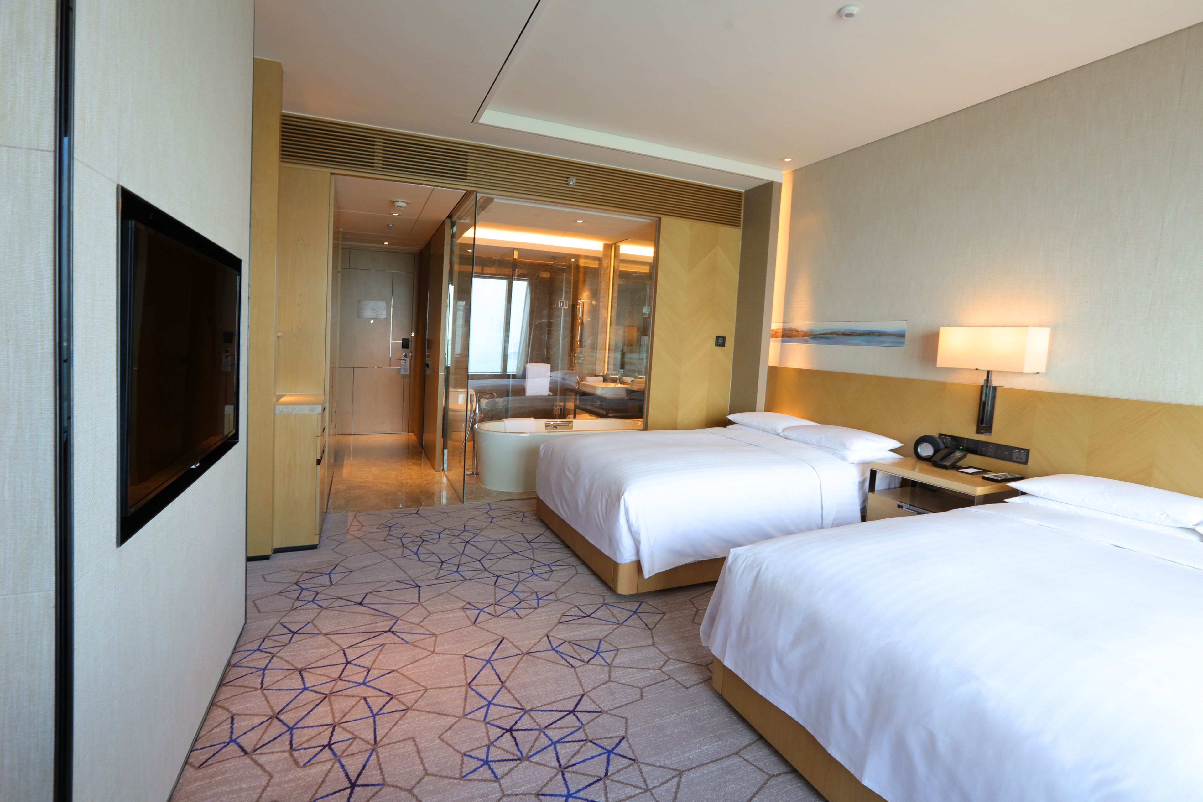 A hotel room with two beds, a bathroom, and a TV.