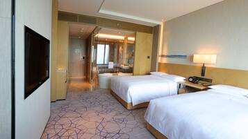 A hotel room with two beds, a bathroom, and a TV.