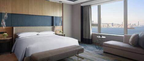Habitación de hotel moderna con una cama grande, un sofá, una mesita y vistas a la ciudad.