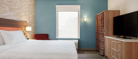 A hotel room with a bed, a TV, a wardrobe, and a window.
