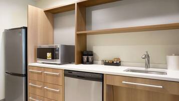 A modern kitchen with a stainless steel refrigerator, a microwave, a dishwasher, and wooden cabinetry.