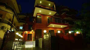 A multi-story hotel with a prominent entrance, balconies, and a well-lit facade. - Hotel Anandam (Gurugram)