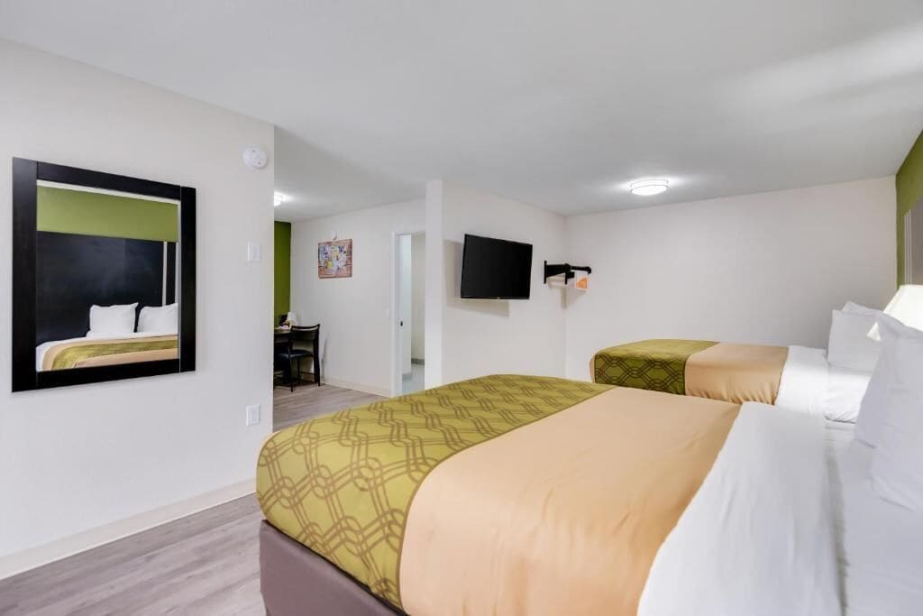 A hotel room with two beds, a flat-screen TV, and a desk with a chair.