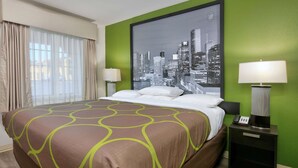 A hotel room with a large bed, green walls, a cityscape view, and a nightstand with a lamp. - Super 8 by Wyndham Palestine (Palestine)