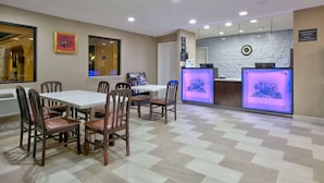 A hotel lobby with a checkered floor, a reception desk, and a dining area with a white table and wooden chairs. - Super 8 by Wyndham Palestine (Palestine)