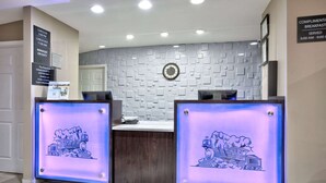A reception desk with a check-in/out sign, a clock, and a complimentary breakfast sign. - Super 8 by Wyndham Palestine (Palestine)