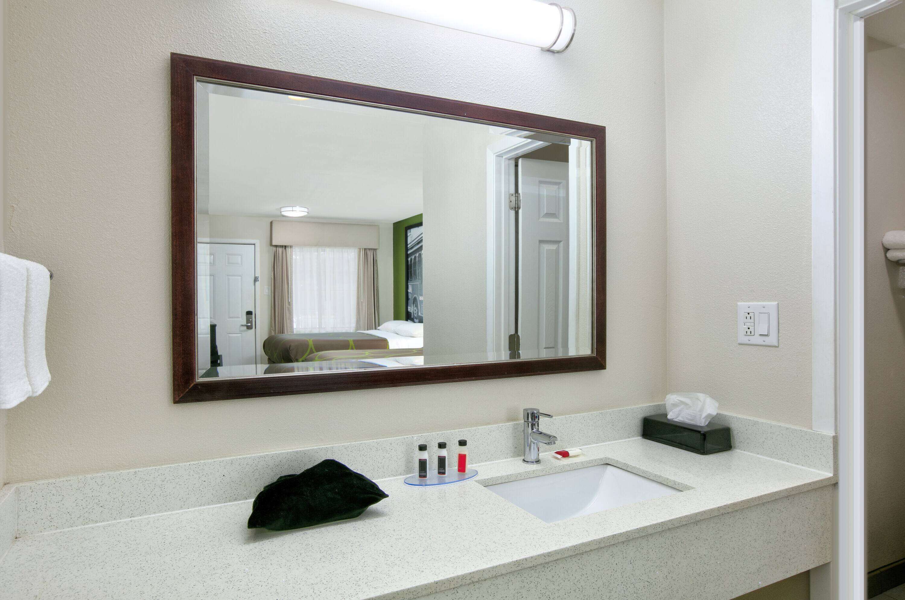 Une salle de bain avec un grand miroir, un lavabo et des articles de toilette.