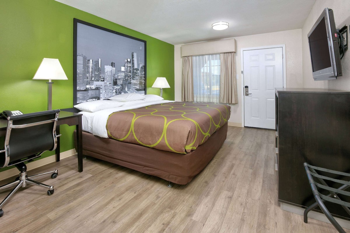 Ett hotellrum med en säng, ett skrivbord, en stol och en tv.