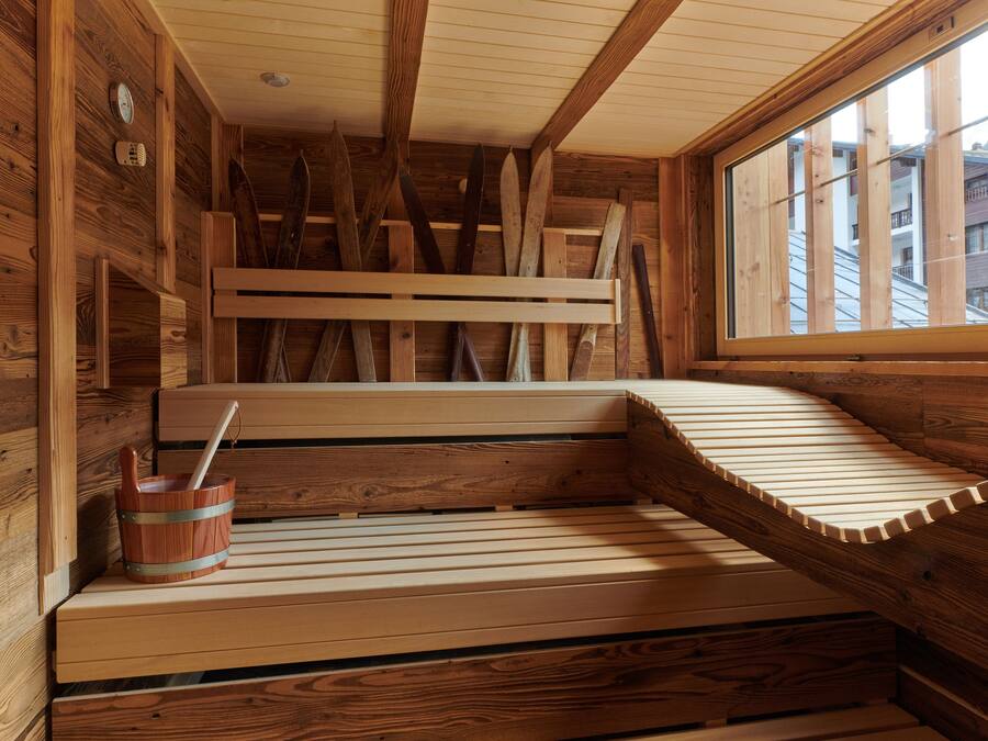 Una sauna de madera con bancos y un cubo de madera.