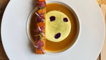 A white plate with a dessert featuring a yellow sphere and a decorative element on the side.