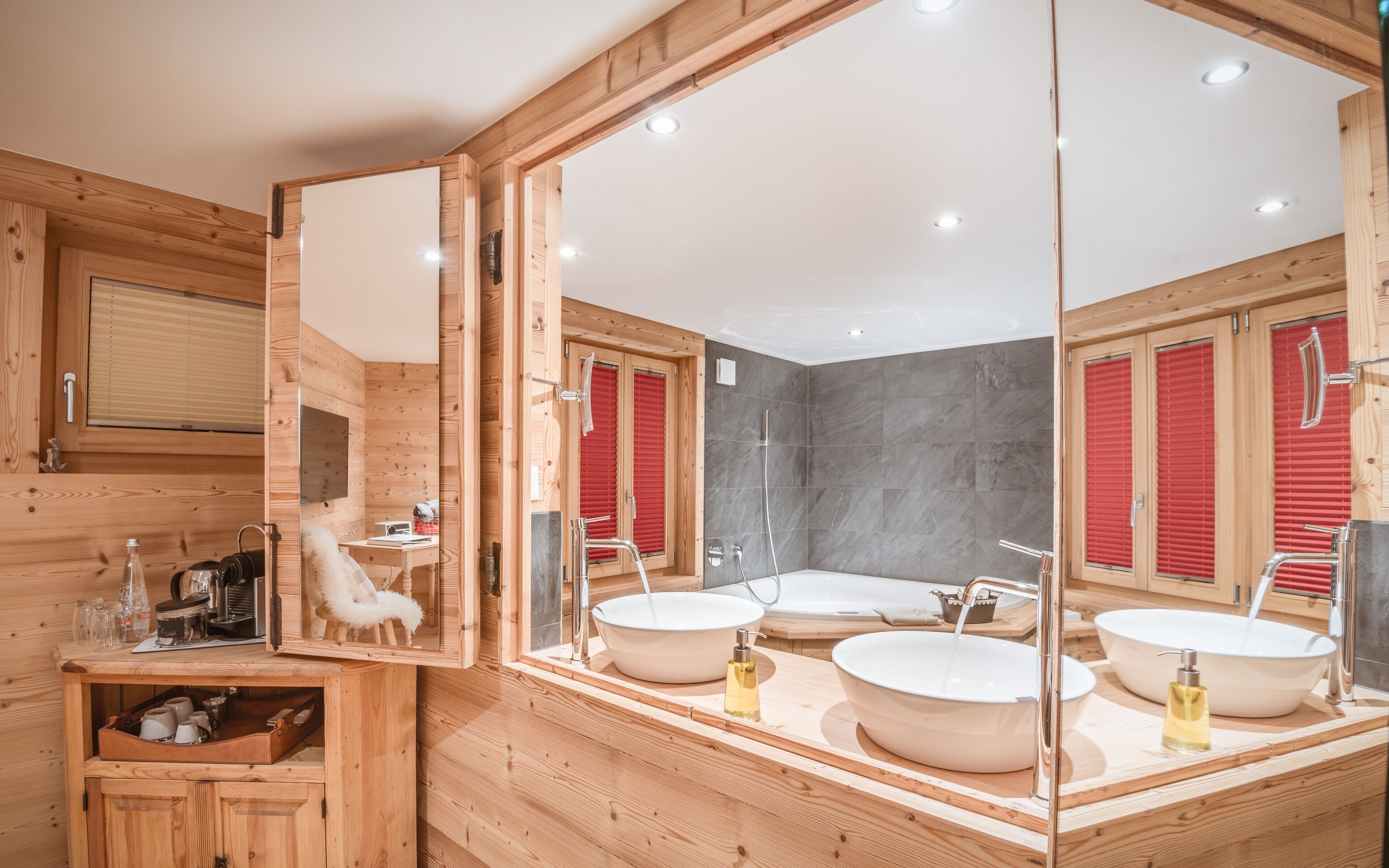 A wooden cabin bathroom with a large mirror, two sinks, and a shower.
