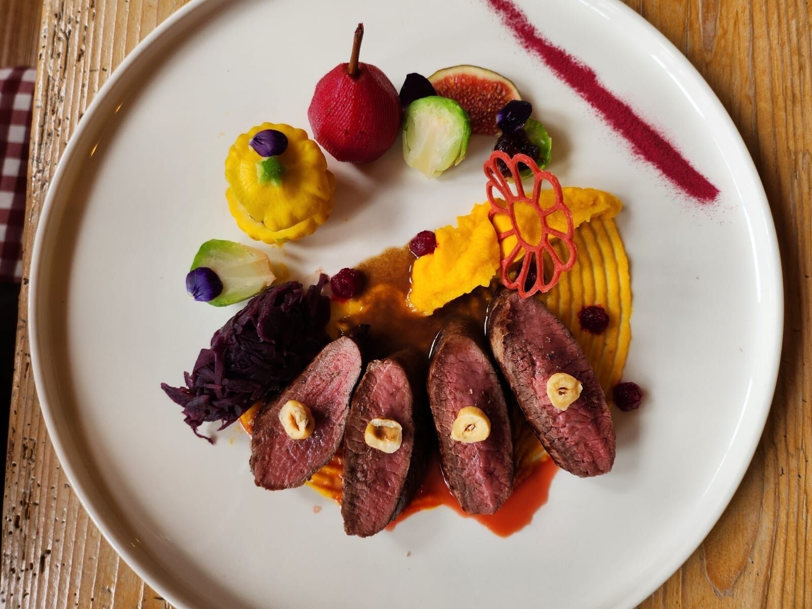 A plate of food with various items including meat, vegetables, and a decorative element.