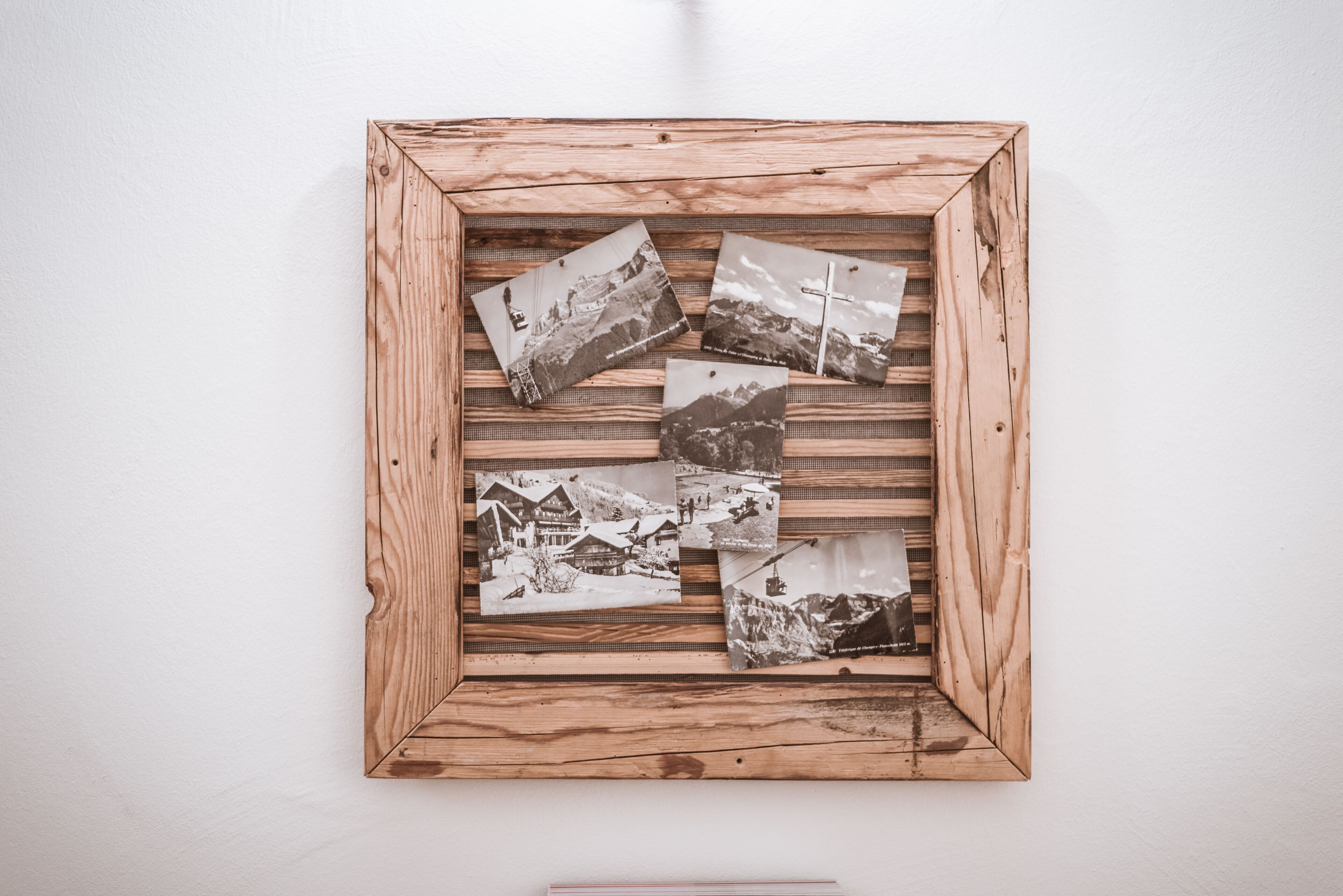 Een houten lijst met zes zwart-witfoto's van besneeuwde landschappen en gebouwen.