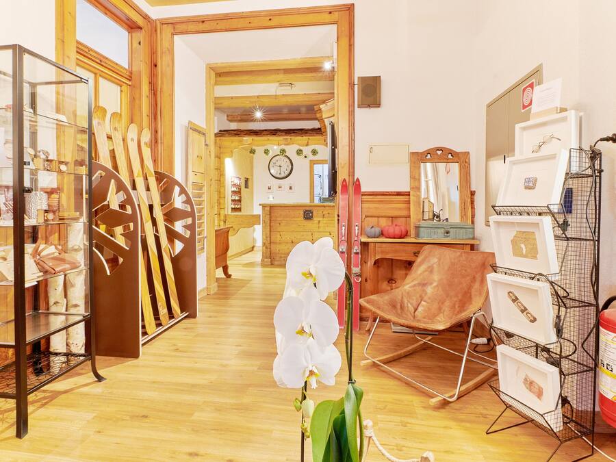 Una habitación con suelo de madera, una vitrina de cristal, un sillón de cuero marrón y una orquídea blanca.