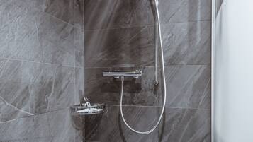 Una ducha moderna con cabezal de ducha de mano y mandos en la pared.