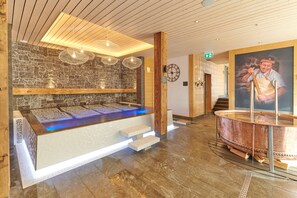 A reception area with a stone wall, wooden ceiling, and a large copper water feature. - Lifestyle Rooms & Suites by Beau-Séjour (Champery)