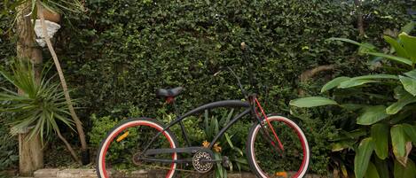 A bicycle parked in a garden with a hedge in the background.