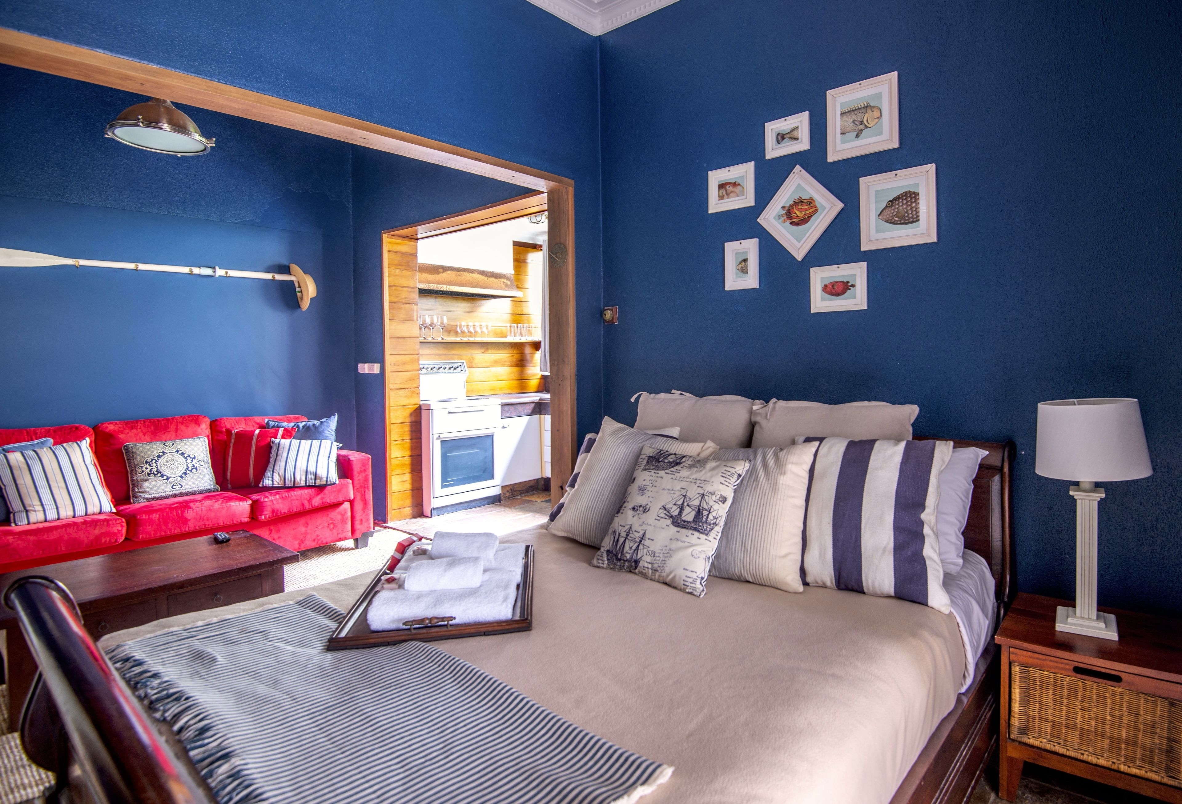 A bedroom with a bed, a red sofa, and a wooden nightstand.