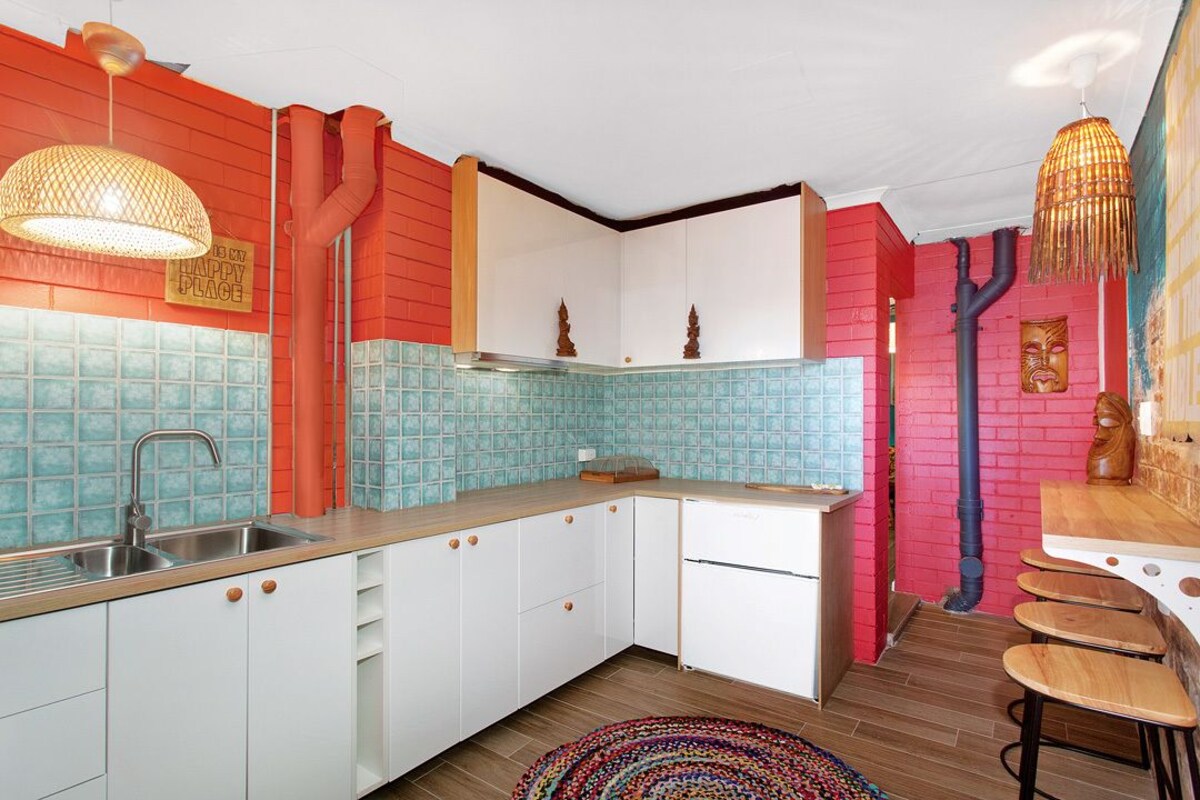 Una cocina con armarios blancos, un lavamanos y un tapete colorido.