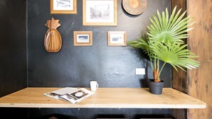 Een houten tafel met een tijdschrift, een witte mok en een bloempot.