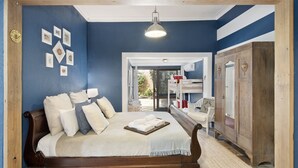 Een slaapkamer met een houten bed, nachtkastje, kledingkast en een wand met ingelijste foto's.