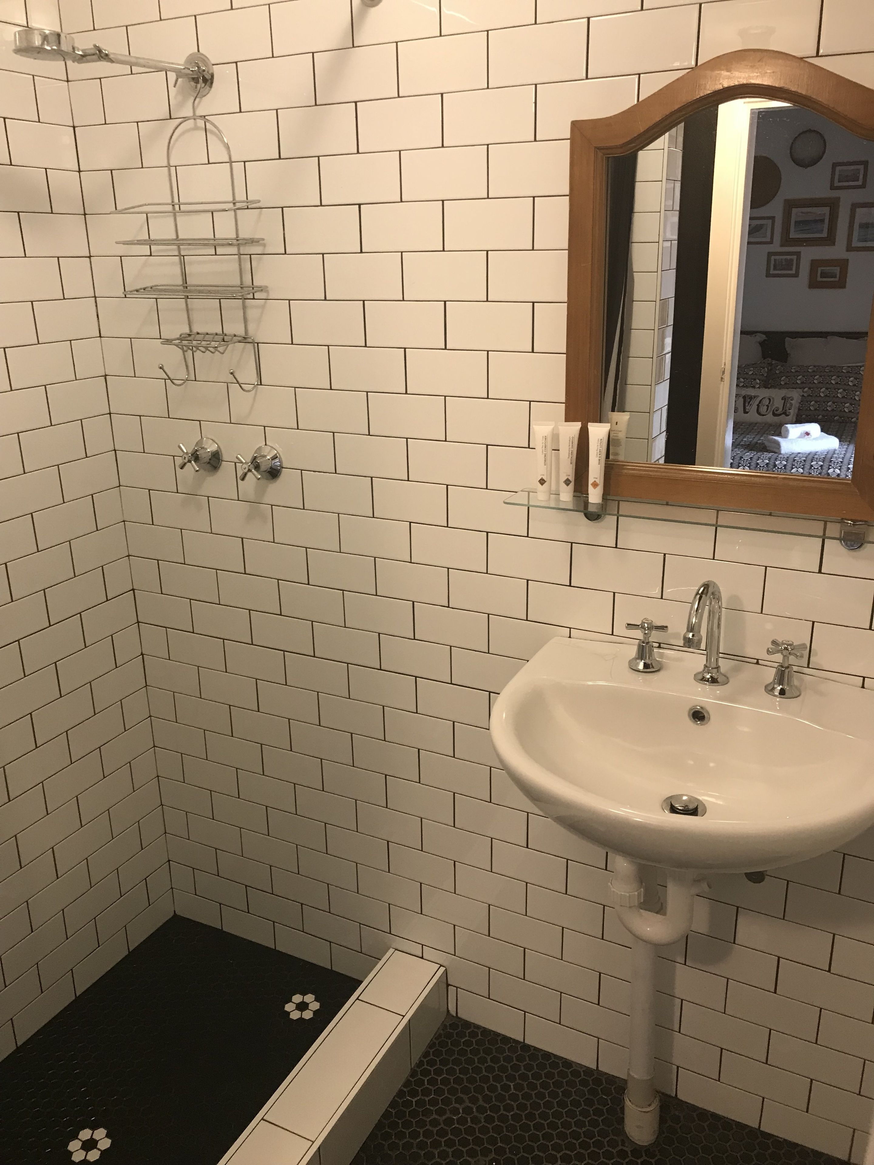 A bathroom with white subway tiles, a white sink with two faucets, and a shower area with a glass shower enclosure.