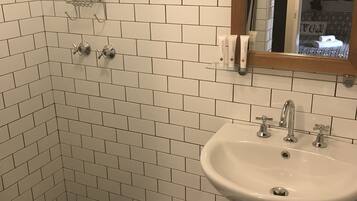 A bathroom with white subway tiles, a white sink with two faucets, and a shower area with a glass shower enclosure.