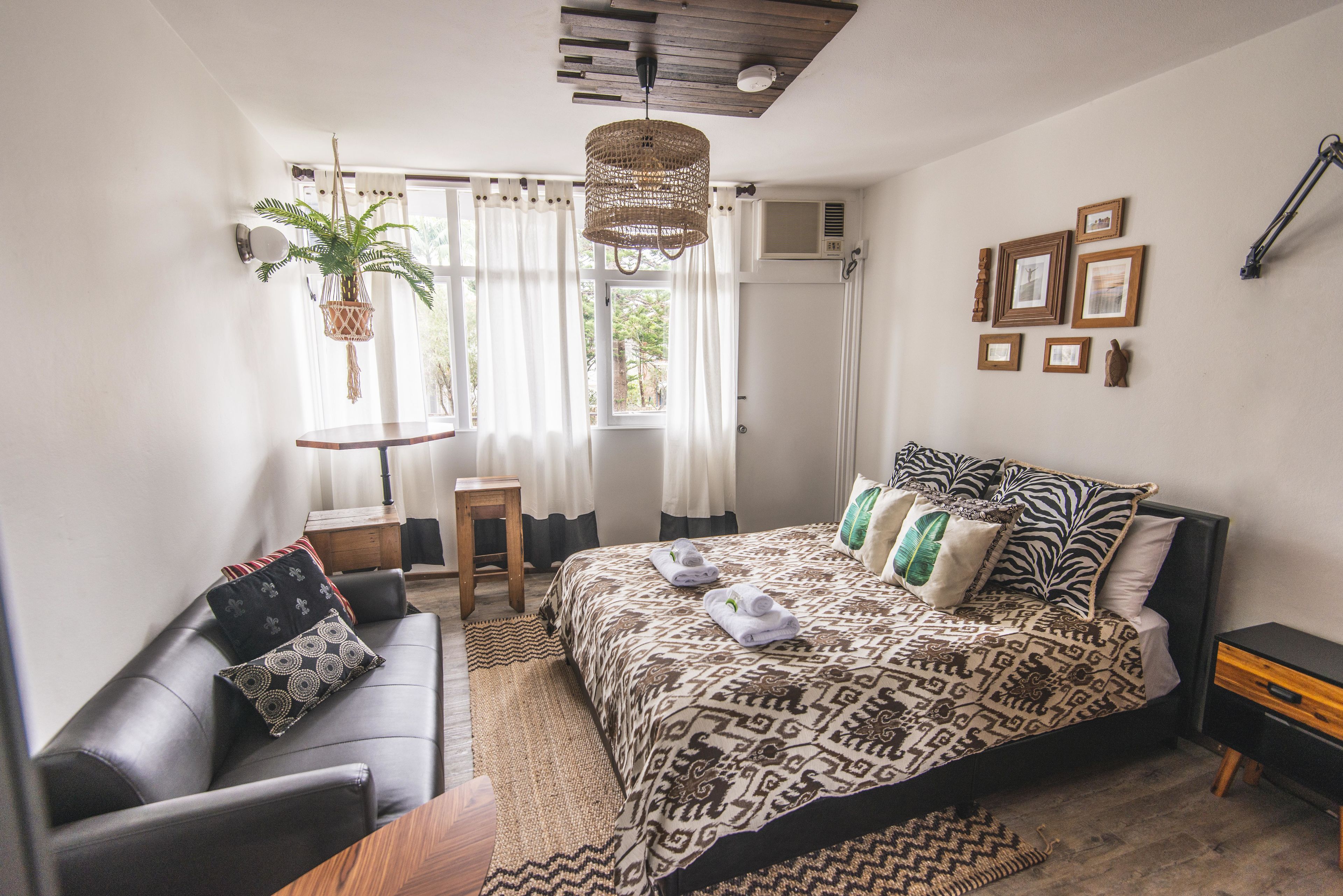 Un dormitorio con una cama grande, una mesita, un sofá y una planta colgante.