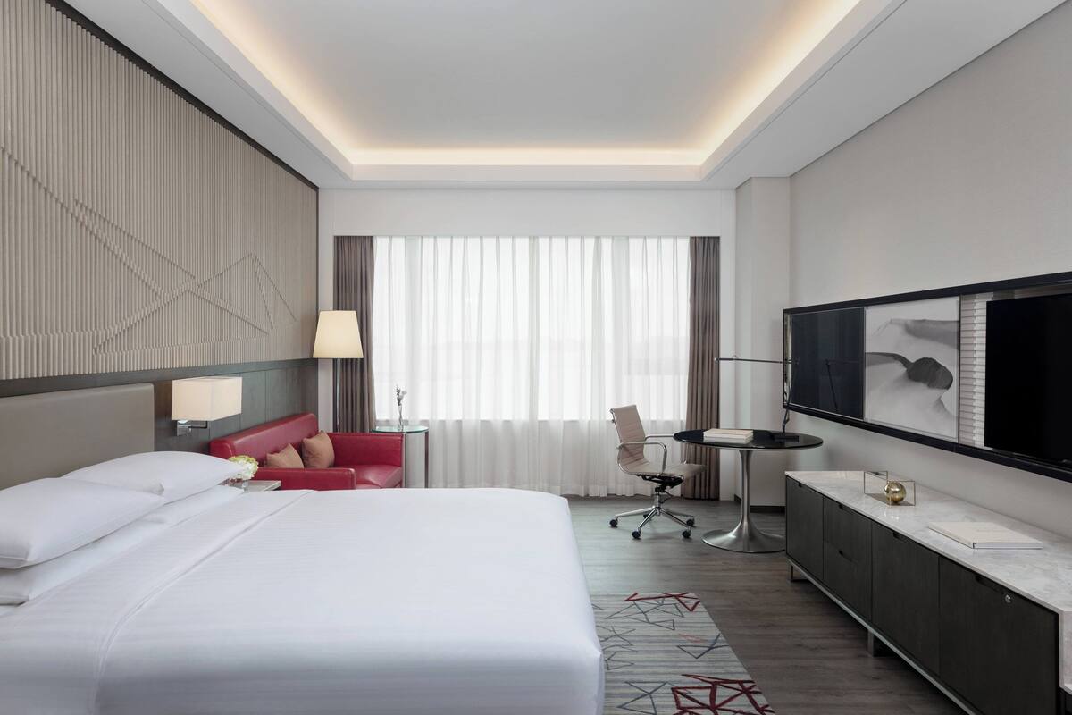 Une chambre d’hôtel avec un grand lit, un canapé rouge, un bureau et une télévision.