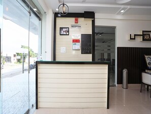 Un comptoir d’accueil avec un panneau indiquant l’heure limite pour quitter les lieux, un détecteur d’incendie et un présentoir à clés fixé au mur.